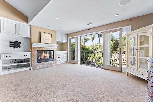 unfurnished living room featuring plenty of natural light, carpet flooring, lofted ceiling, and a fireplace