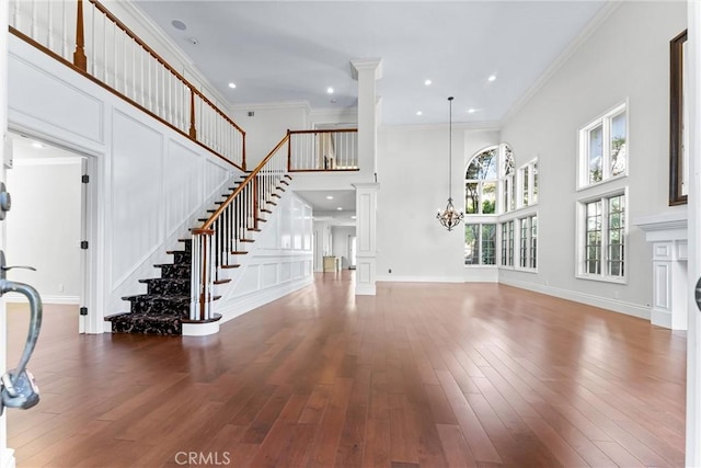 unfurnished living room with ornamental molding, wood-type flooring, and a notable chandelier