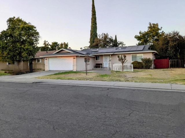 ranch-style house with solar panels, a garage, and a front yard