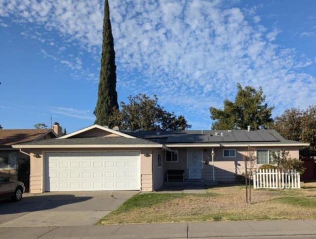 single story home with a garage and solar panels