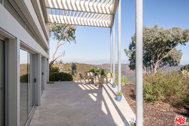 view of patio / terrace with a pergola and a mountain view