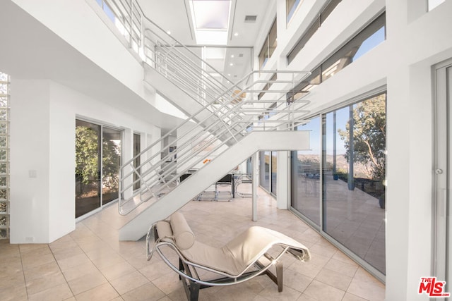 tiled living room featuring a skylight, a high ceiling, and plenty of natural light