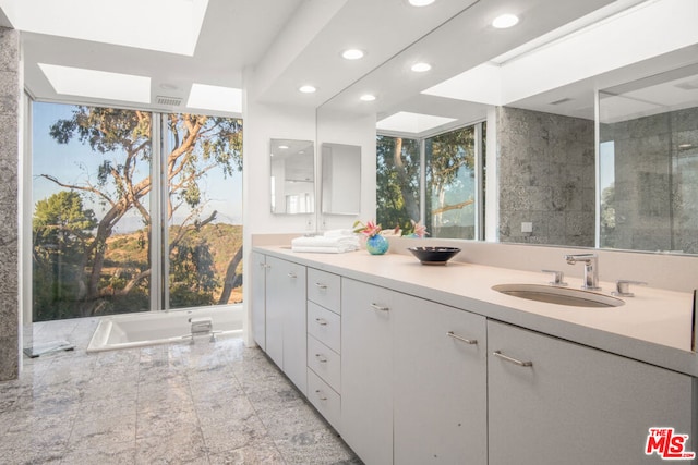 bathroom featuring vanity, shower with separate bathtub, and a skylight