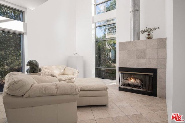 living area featuring a towering ceiling, a tile fireplace, and light tile patterned floors