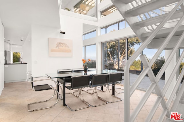 dining area with a towering ceiling, light tile patterned flooring, and plenty of natural light