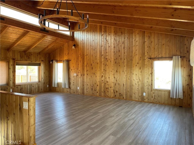 unfurnished living room with vaulted ceiling with beams, wood walls, hardwood / wood-style floors, and wooden ceiling