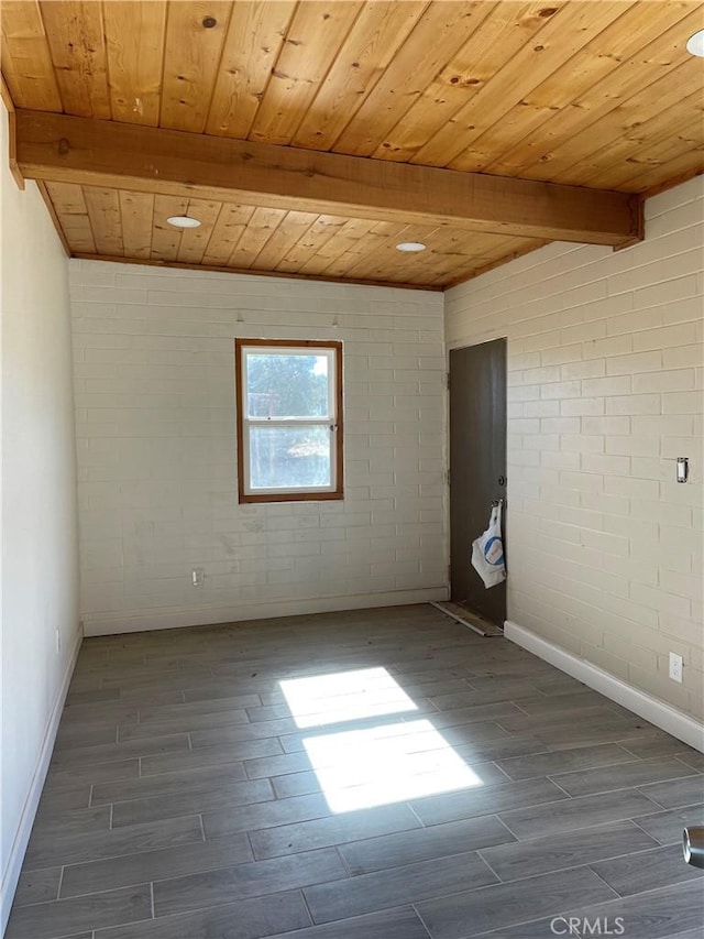 spare room with dark hardwood / wood-style flooring, beamed ceiling, wood ceiling, and brick wall