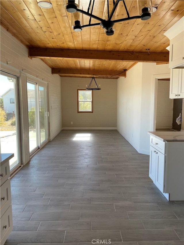 unfurnished dining area featuring beamed ceiling, wood-type flooring, and wooden ceiling