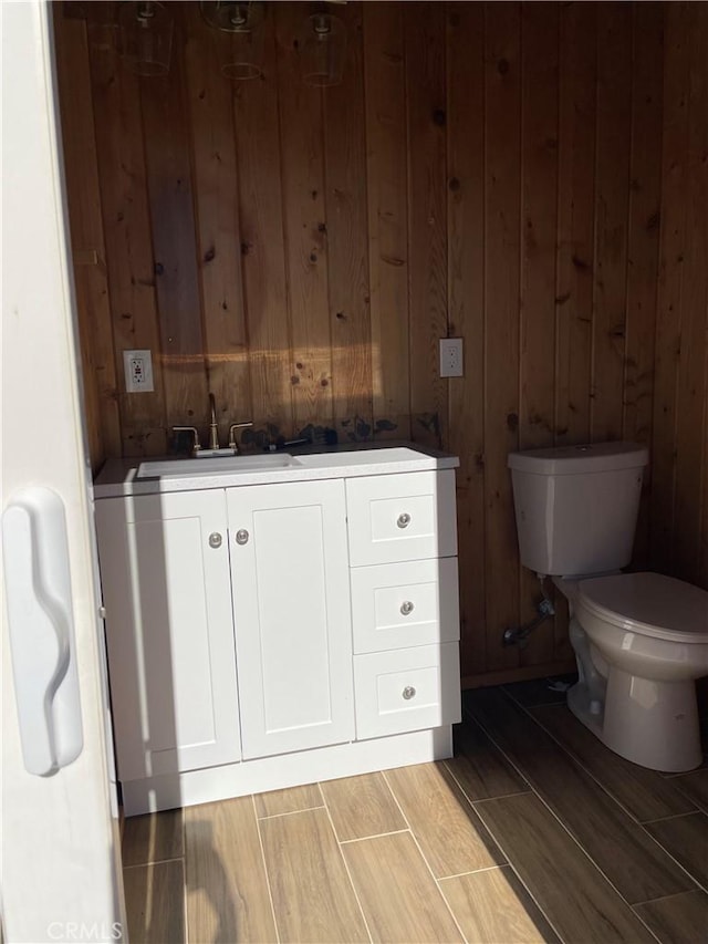 bathroom with vanity, toilet, and wooden walls