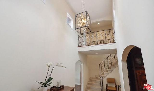 stairs featuring an inviting chandelier, a high ceiling, and hardwood / wood-style flooring