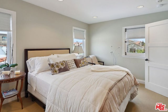 bedroom featuring light carpet and multiple windows