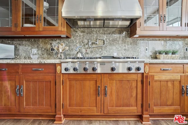 kitchen with light stone countertops, light hardwood / wood-style floors, and exhaust hood