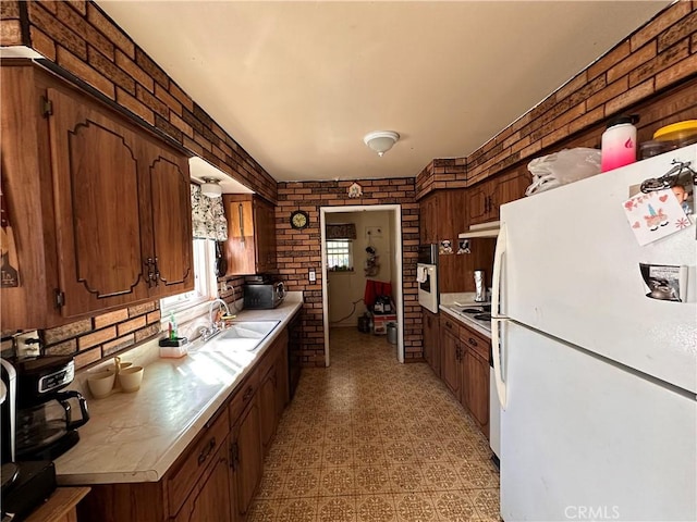 kitchen featuring appliances with stainless steel finishes, sink, and brick wall