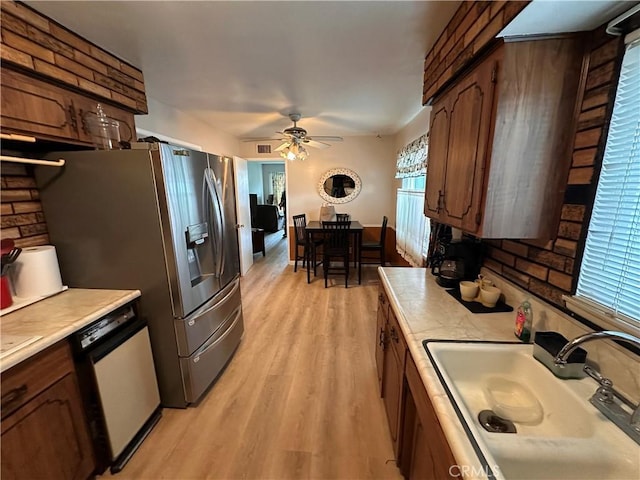 kitchen with dishwasher, light wood-style flooring, light countertops, and a sink