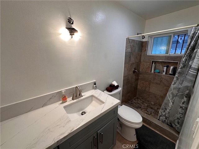 full bath with a tile shower, vanity, and toilet