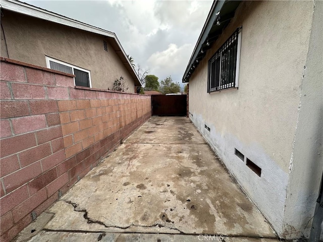 view of property exterior featuring crawl space, a patio area, fence, and stucco siding