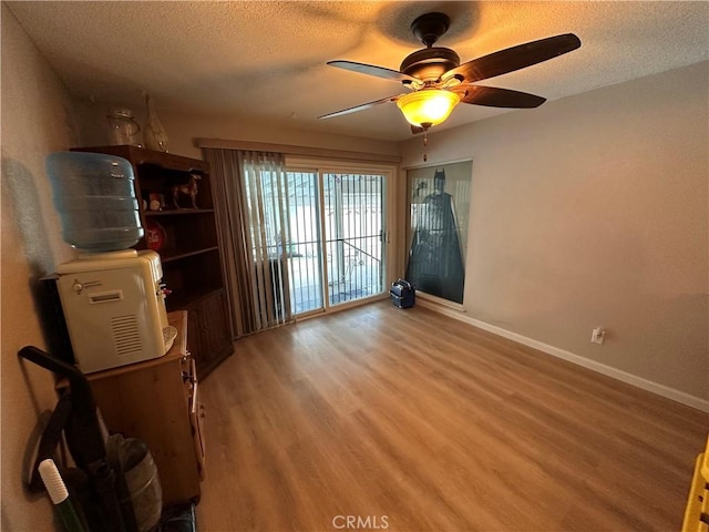 interior space featuring baseboards, a textured ceiling, and light wood finished floors