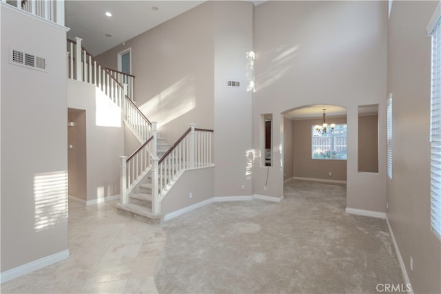 interior space with a notable chandelier, light colored carpet, and a towering ceiling