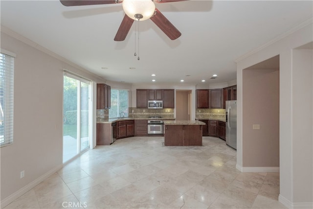 kitchen with ornamental molding, stainless steel appliances, backsplash, and a kitchen island