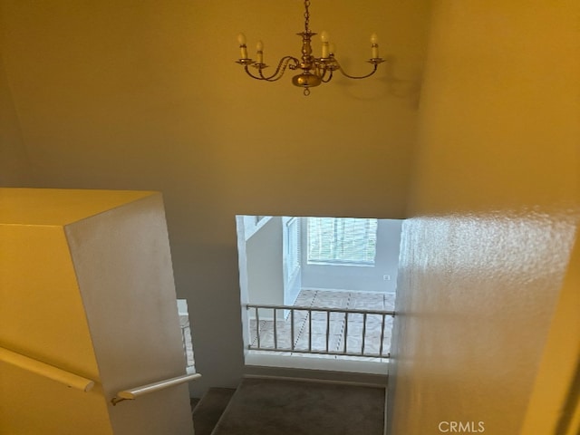 stairway with a chandelier and carpet flooring