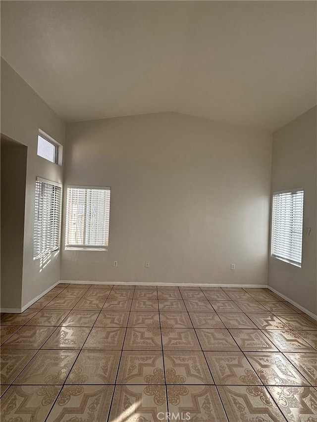 empty room with lofted ceiling and light tile patterned flooring