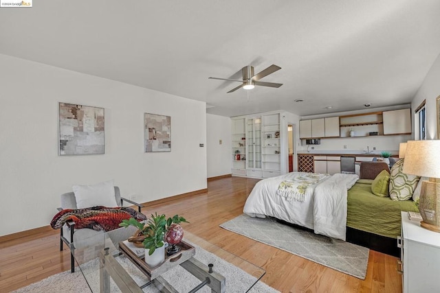 bedroom featuring light hardwood / wood-style flooring, ceiling fan, and sink