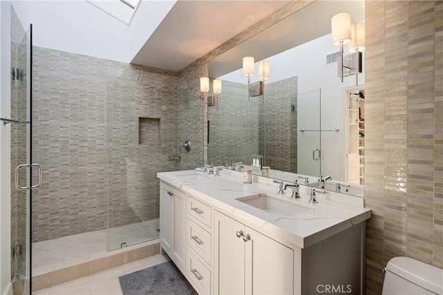 bathroom with a skylight, vanity, tile patterned floors, toilet, and walk in shower