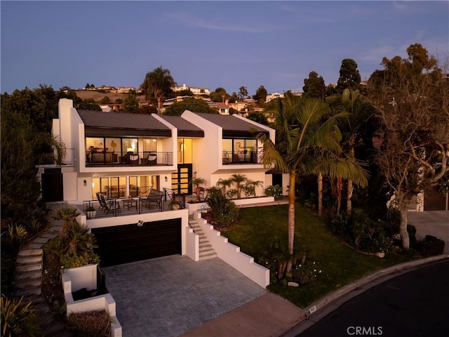 view of front of property with a garage, a balcony, and a lawn