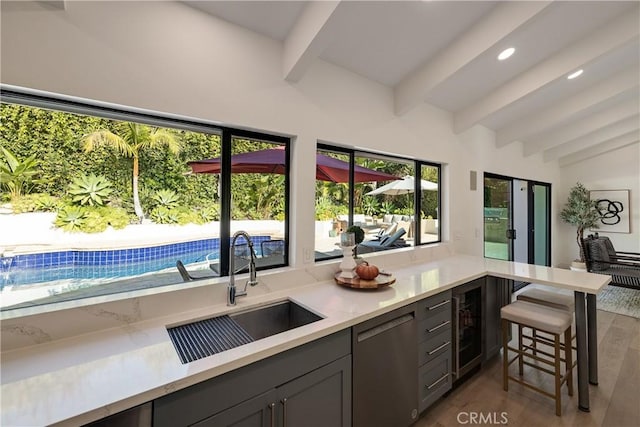 kitchen featuring sink, wood-type flooring, plenty of natural light, dishwasher, and beamed ceiling