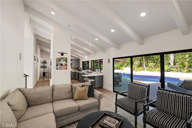 living room with light hardwood / wood-style floors and vaulted ceiling with beams