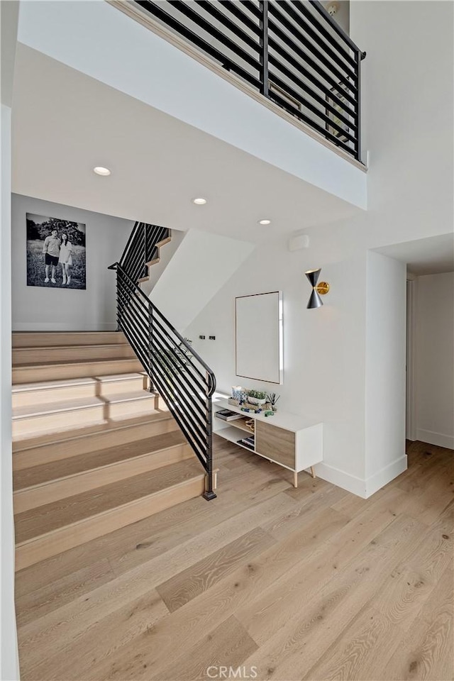 stairway with hardwood / wood-style floors and a towering ceiling