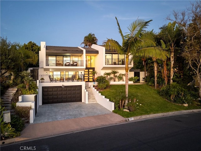 view of front of home with a yard, a garage, and a balcony