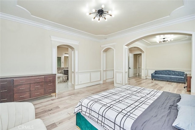 bedroom featuring a chandelier, ensuite bathroom, light hardwood / wood-style flooring, and ornamental molding