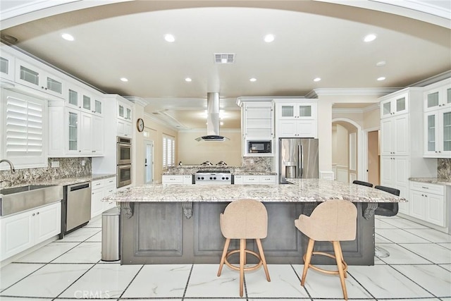 kitchen with sink, stainless steel appliances, light stone counters, a large island with sink, and white cabinets