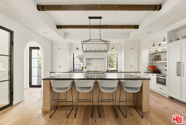 kitchen with white cabinetry, a spacious island, and light wood-type flooring