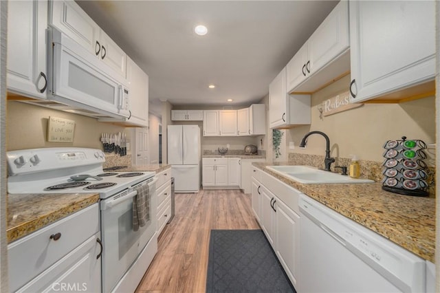 kitchen with white cabinetry, sink, light hardwood / wood-style floors, and white appliances