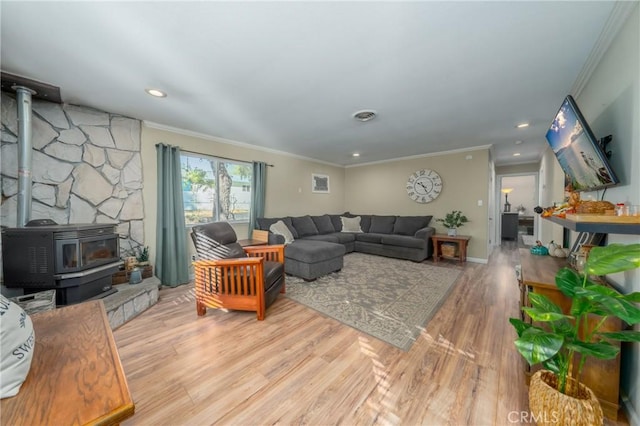 living room featuring a wood stove, light hardwood / wood-style flooring, and crown molding