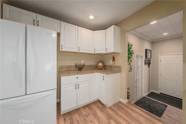 kitchen featuring white fridge, white cabinetry, light stone counters, and light wood-type flooring