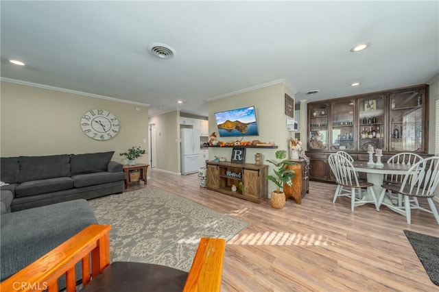 living room with ornamental molding and light hardwood / wood-style floors