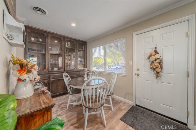 dining space featuring crown molding and light wood-type flooring