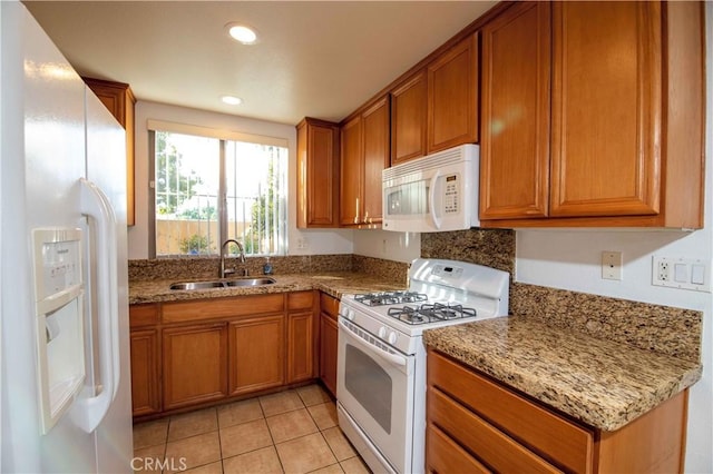 kitchen featuring light tile patterned floors, white appliances, light stone counters, and sink