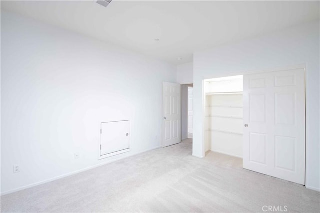 unfurnished bedroom featuring light carpet and a closet