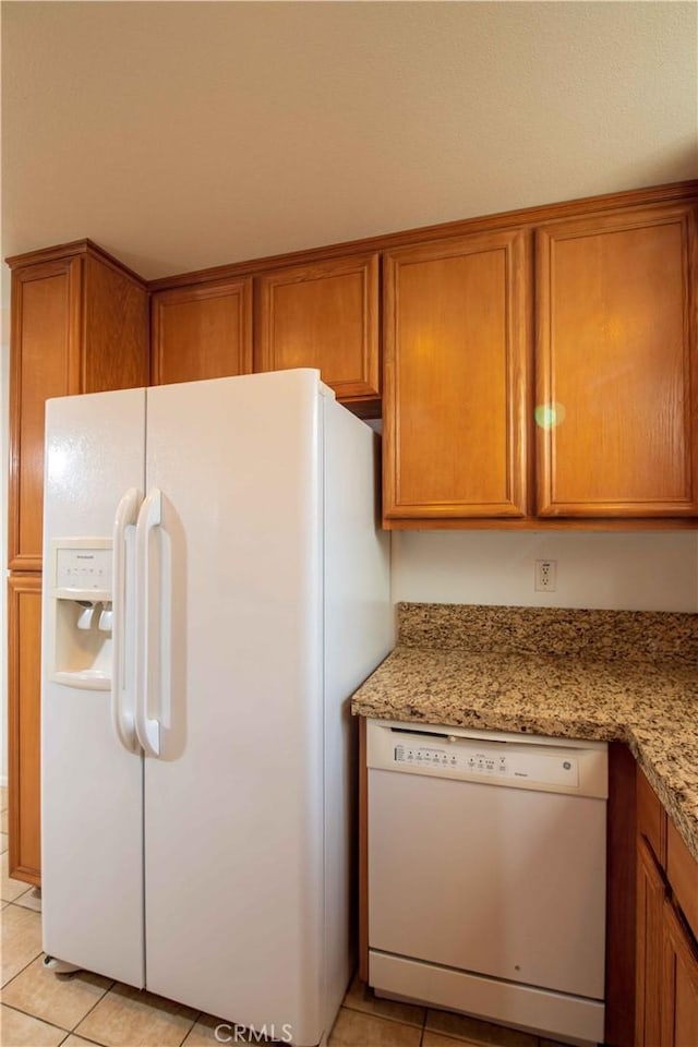 kitchen with light stone countertops, light tile patterned floors, and white appliances