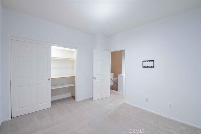 unfurnished bedroom with light colored carpet, a walk in closet, and a closet