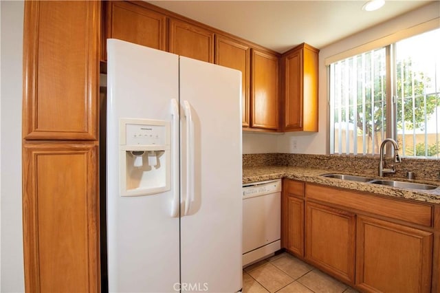 kitchen featuring light tile patterned flooring, light stone counters, white appliances, and sink