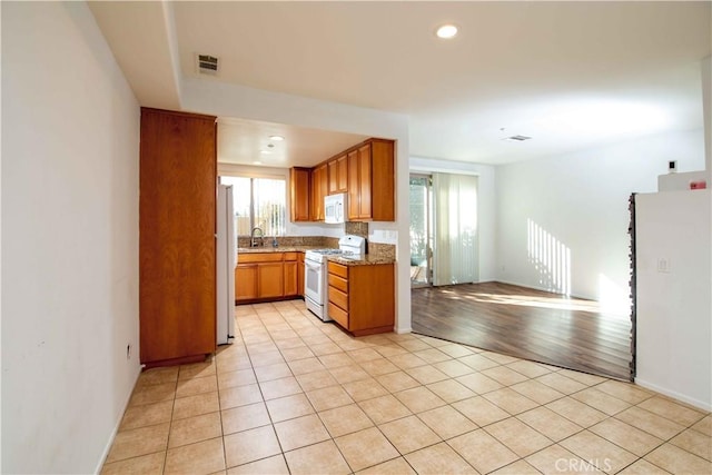 kitchen featuring light stone countertops, white appliances, and light hardwood / wood-style flooring