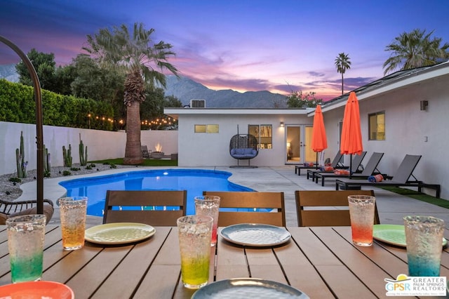 pool at dusk with a patio area and a mountain view