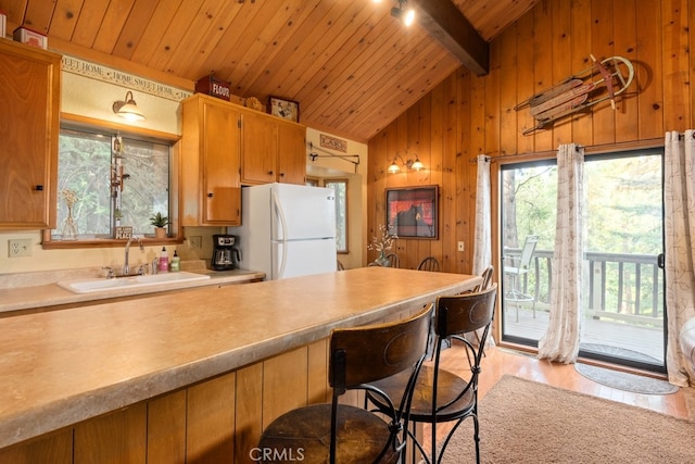 kitchen featuring sink, light wood-type flooring, vaulted ceiling with beams, wooden ceiling, and white refrigerator