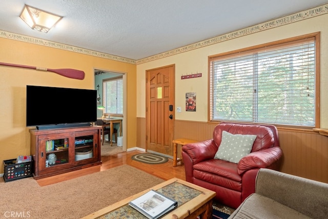 living room featuring a healthy amount of sunlight, wood-type flooring, a textured ceiling, and wood walls