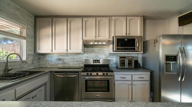 kitchen with tasteful backsplash, sink, white cabinets, and stainless steel appliances